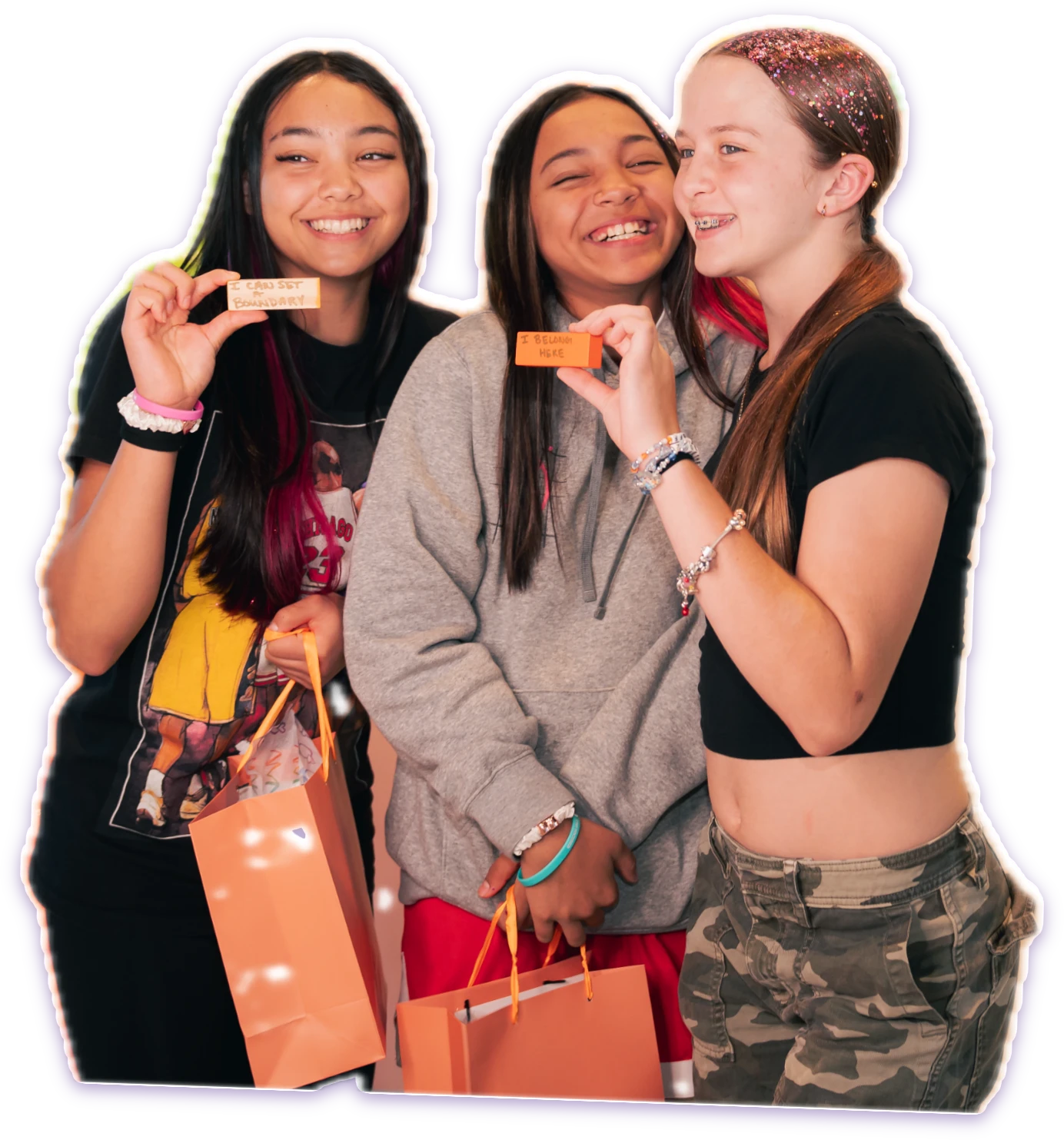 Three friends laughing and holding up handwritten affirmation notes